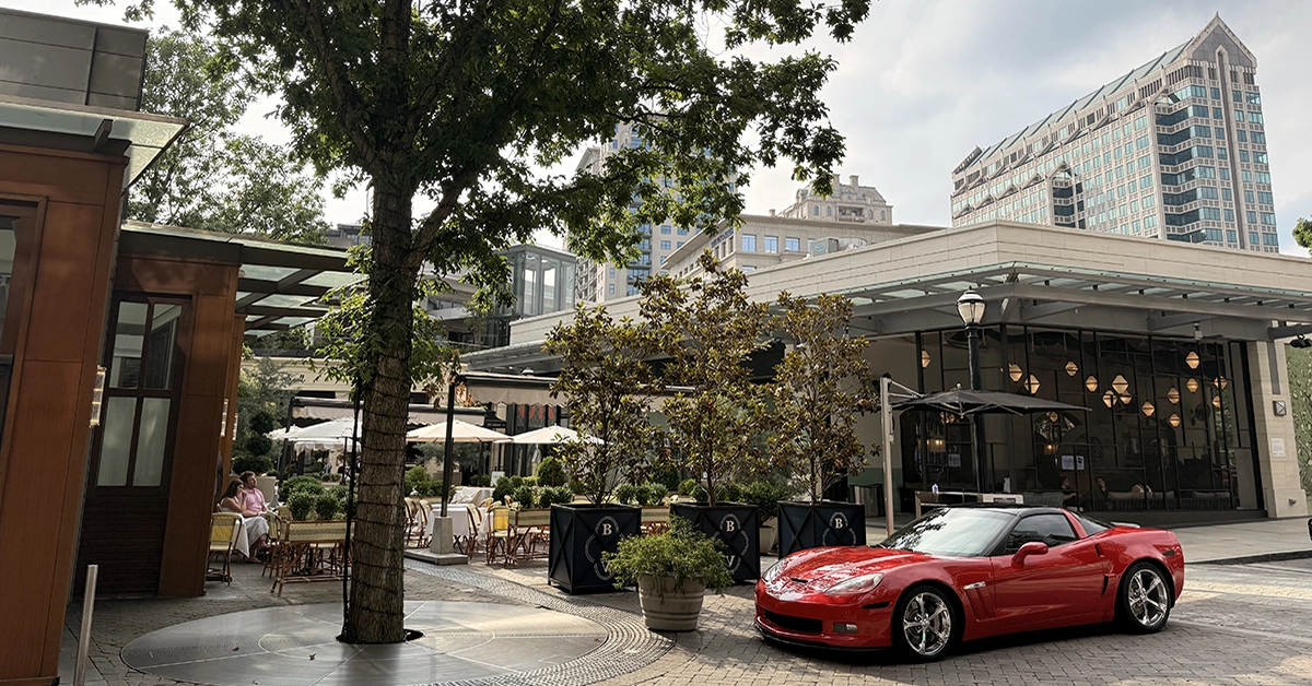 A red sports car is parked on a cobblestone plaza